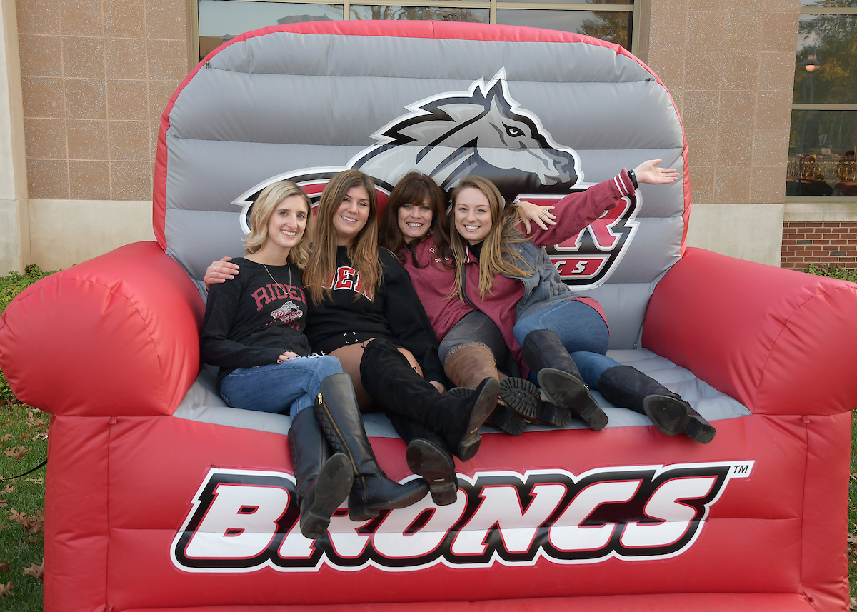 Four women sit on blow-up chair that says "Broncs"