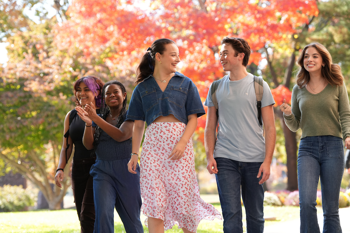 Five students walk across campus