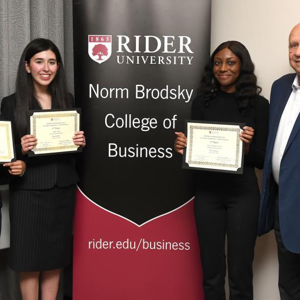 Three student pose with Norm Brodsky at competition