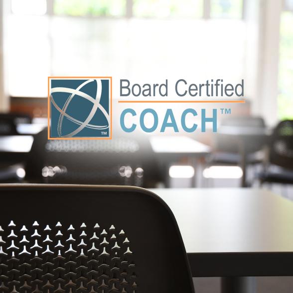 Desk and chairs in a classroom. Board Certified Coach logo.