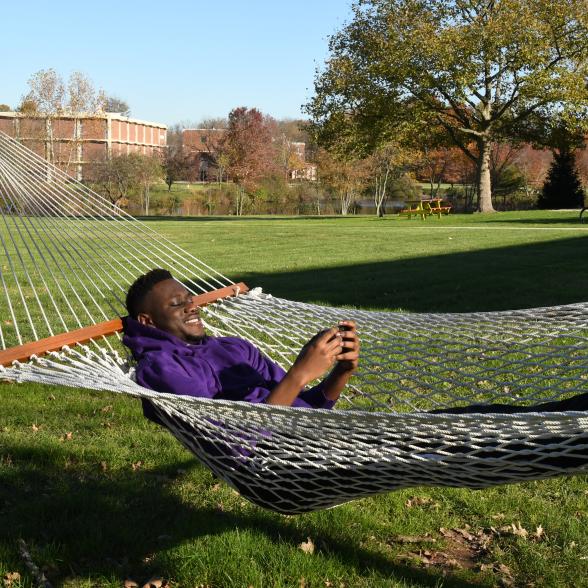 student in hammock on cell phone