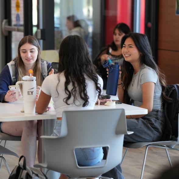 Three students sit at a table in Saxbys cafe