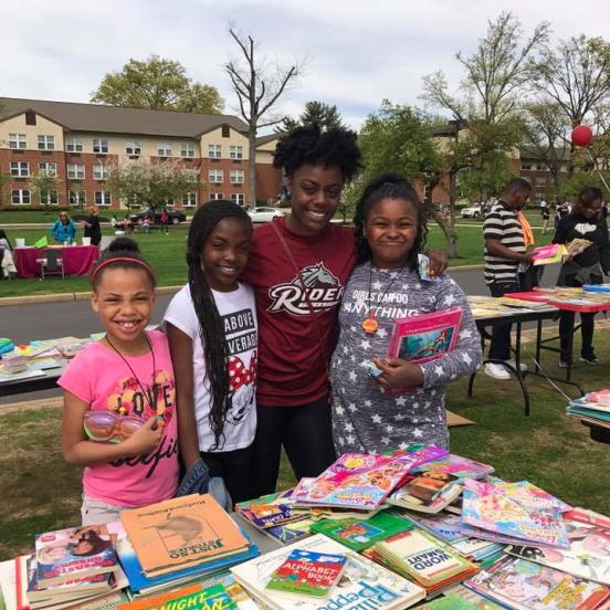 Student poses with kids at book fair.