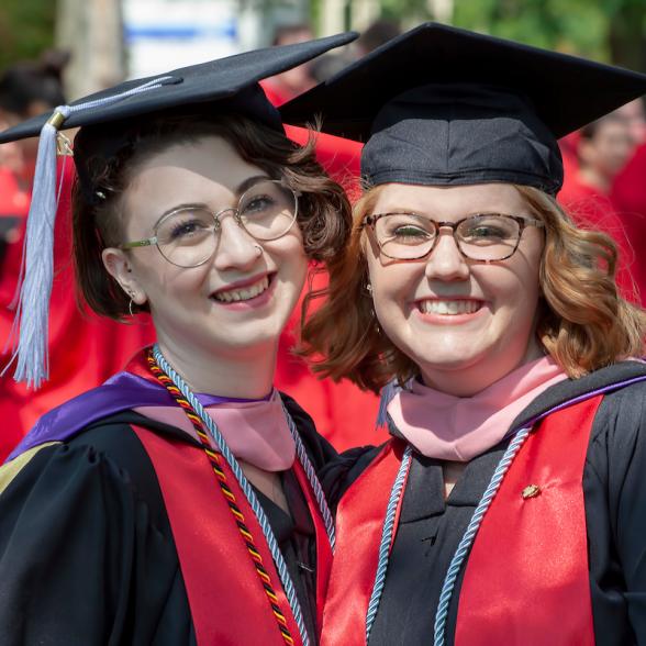 Two students pose for photos at Commencement