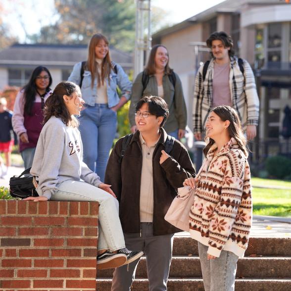 Group of three students sits outside and talks