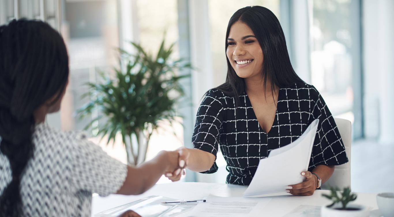 Two young businesswomen shaking hands in a modern office stock photo