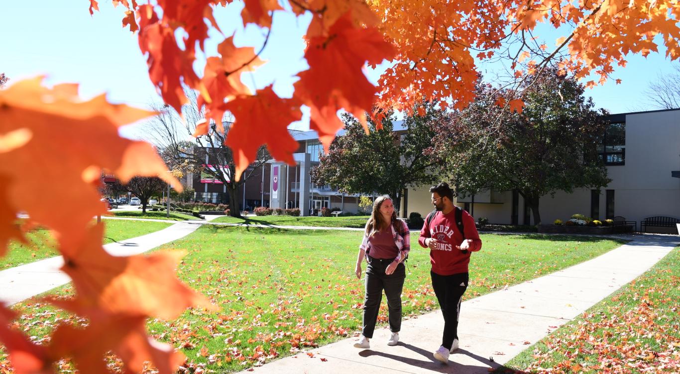 Two students walk on campus in fall