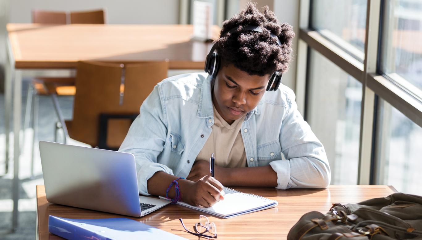 Student studying at a desk with headphones on.