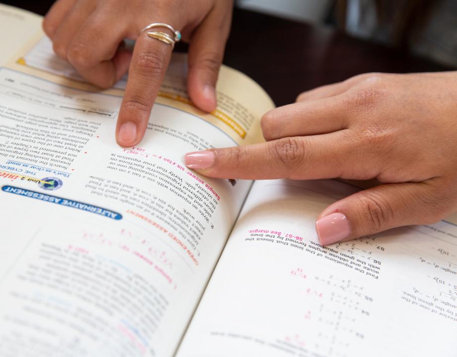 Students pointing in math textbook