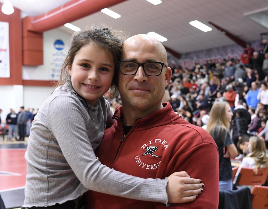 Rider Alumnus poses with daughter at Rider wrestling event.