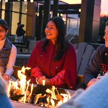 Students sit outside around firepit