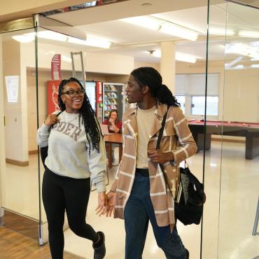 Two students walk through residence hall doorway