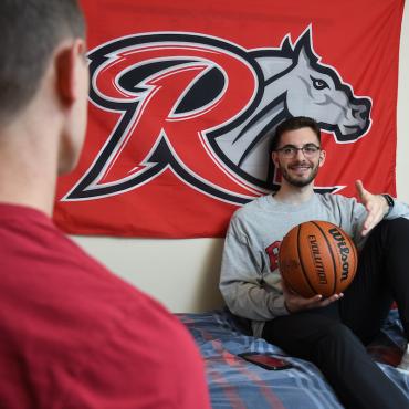 Student holds basketball while talking to roommate