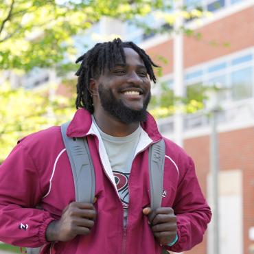 Male student in red Rider jacket walks to class